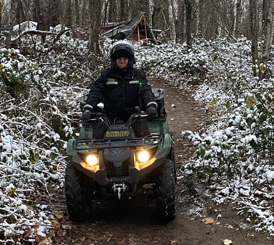 Sergeant on ATV in wooded area.