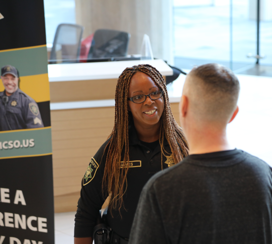 Deputy talks with job seeker at hiring event.