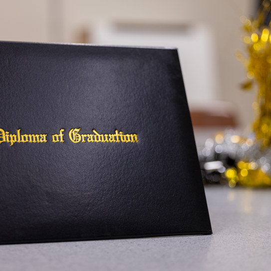 a black folder embossed with 'Diploma of Graduation'