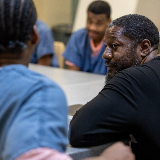 Nathanyel Israel sits at a table alongside adults in custody enrolled in his ManUp Program.