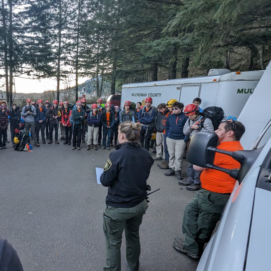 Group of search and rescue volunteers gathers for briefing with deputies.