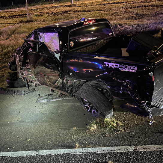 A black pickup truck is shown on the freeway at night crashed after rolling over. 