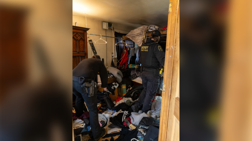 A Multnomah County deputy sheriff and a TriMet Transit police officer search inside a home following a court-authorized search warrant. 