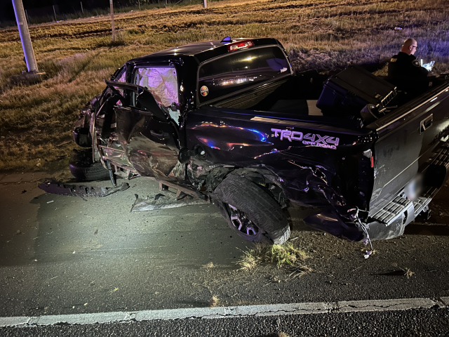 A black pickup truck is shown on the freeway at night crashed after rolling over. 