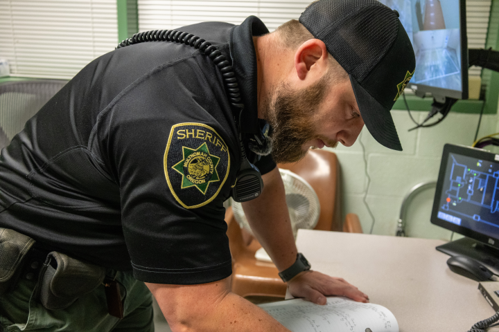 Corrections Deputy Blaesing fills out the jail log at the start of his shift.