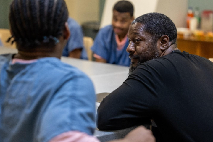 Nathanyel Israel sits at a table alongside adults in custody enrolled in his ManUp Program.