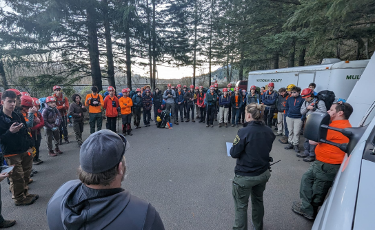 Group of search and rescue volunteers gathers for briefing with deputies.