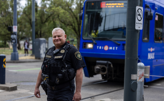 Lt. Lichatowich stands on the Rose Quarter TriMet Max platform as a Max train passes behind him