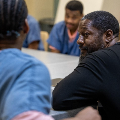 Nathanyel Israel sits at a table alongside adults in custody enrolled in his ManUp Program.