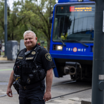 Lt. Lichatowich stands on the Rose Quarter TriMet Max platform as a Max train passes behind him
